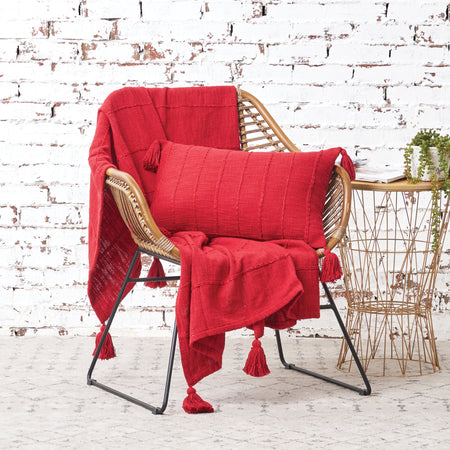 red hand woven throw with fringed edges with a matching pillow on a chair