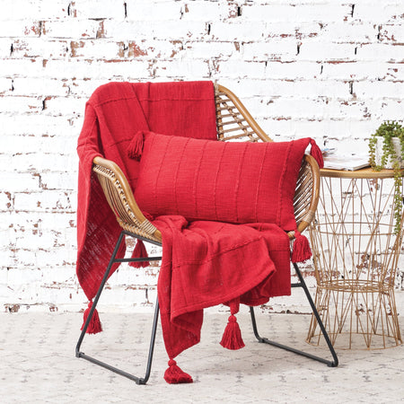 red cotton slub pillow with fringed edges and a matching throw on a chair