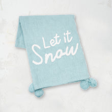 light blue woven throw with pom pom edges and the words let it snow in white