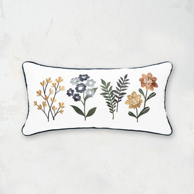 Pillow embroidered with foliage and abstract flowers on a white background with a blue trim