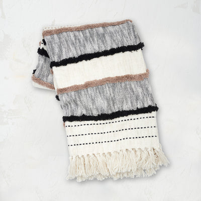 Benn Onyx Throw styled with woven horizontal patterns, tufted textures, and finished with hand-tied tassels.