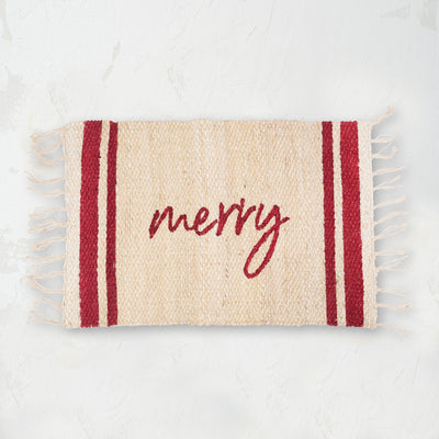 holiday jute rug with holly red text that says the word merry